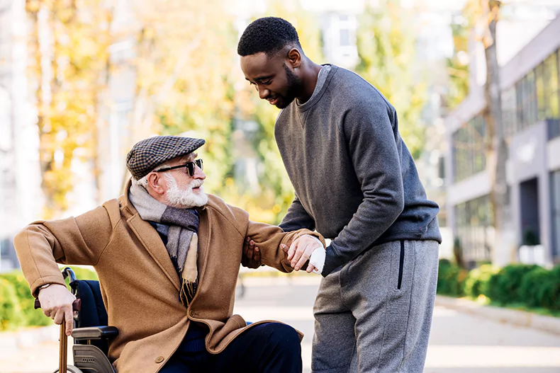 home health care aide helping an elderly man in a wheelchair.webp